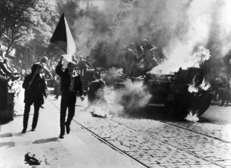 Czechoslovaks carry their national flag past a burning Soviet tank in Prague, Jan.,1968.