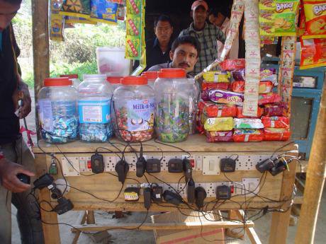 A shopkeeper charging mobile phones in the village of Gohpur, Assam in India