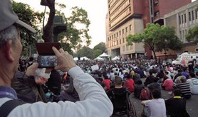 Elderly man uses his smartphone to video record the large crowd gathered on Jinan Road