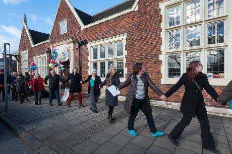 Library supporters link arms and walk past the frontage of the Friern Barnet Community Library