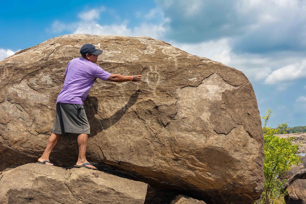 El hombre sube a la roca para mostrar el arte indígena
