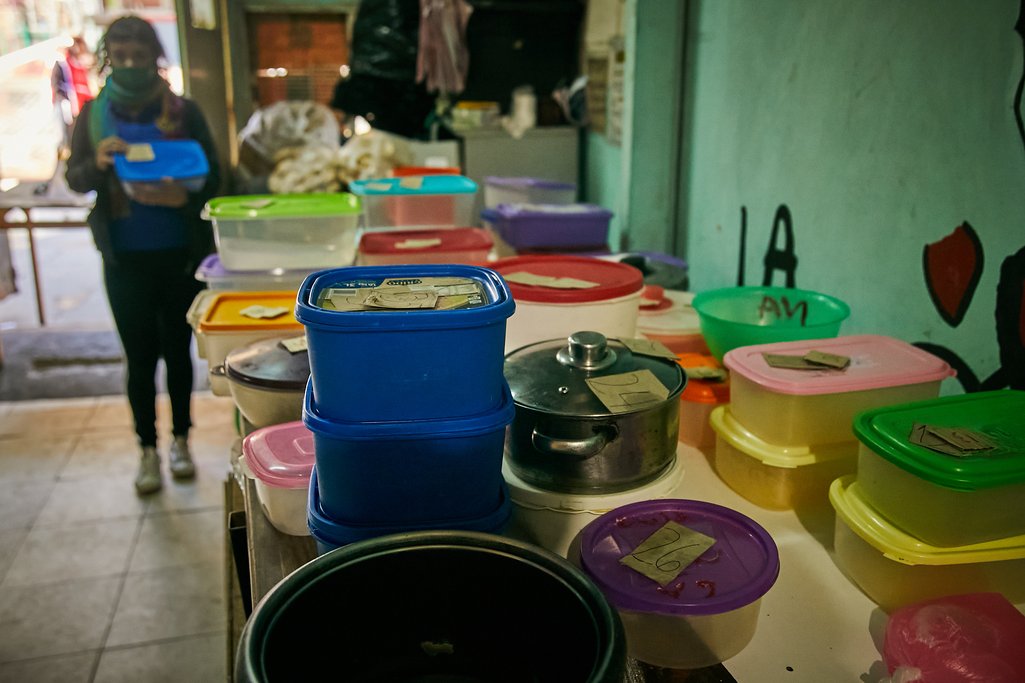Cooks at the 'Gustavo Cortiñas' community kitchen receive daily hundreds of plastic containers they fill with food and serve at midday