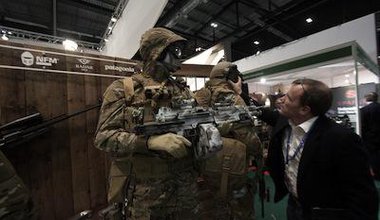 A visitor inspects soldiers wearing camouflage suits at the DSEI arms fair in London, 2013.
