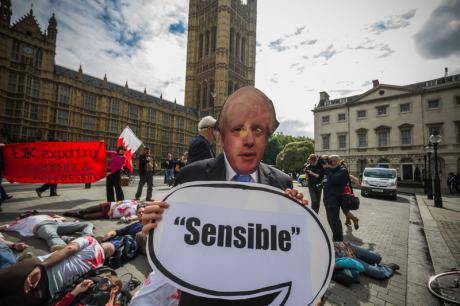Protestors against the arms trade mimic Boris Johnson outside Parliament