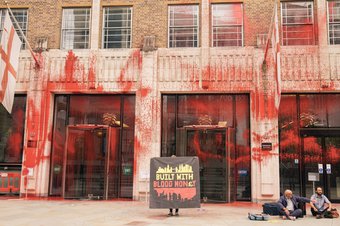 Sign reading "BUILT WITH BLOOD MON£Y" in front of Guildhall covered in fake blood on day 5 of Extinction Rebellion protests in London 27 August 2021