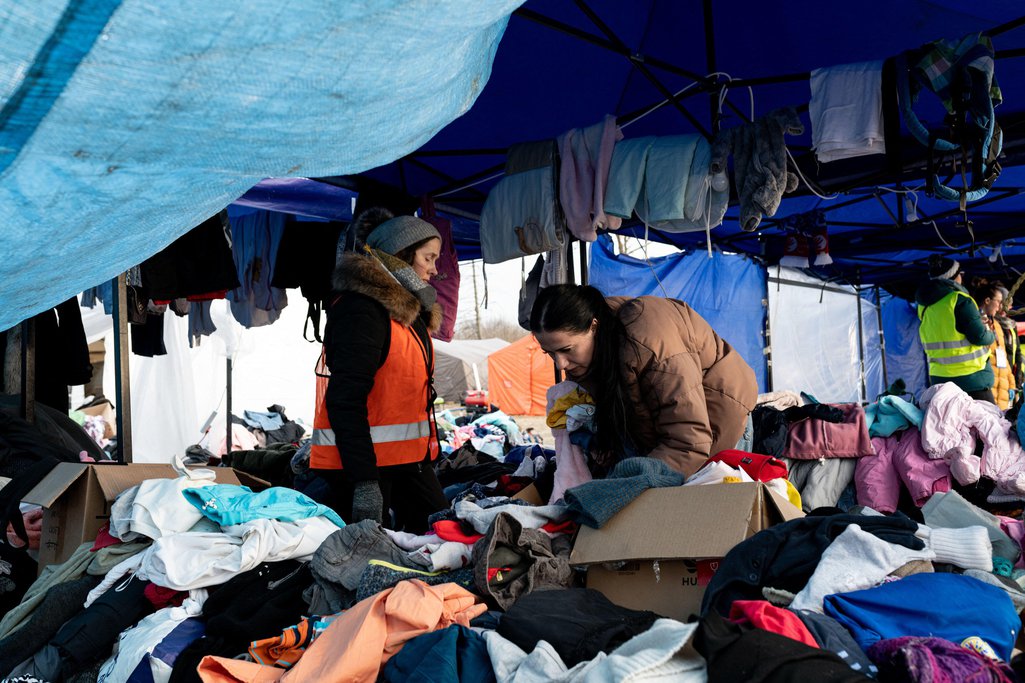 A woman looks for clothes among the stacked goods given by humanitarians at the refugee camp 