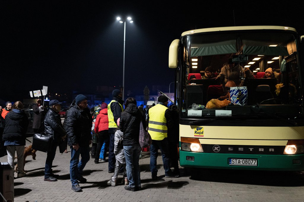 Refugees exit a bus arriving at the refugee centre 