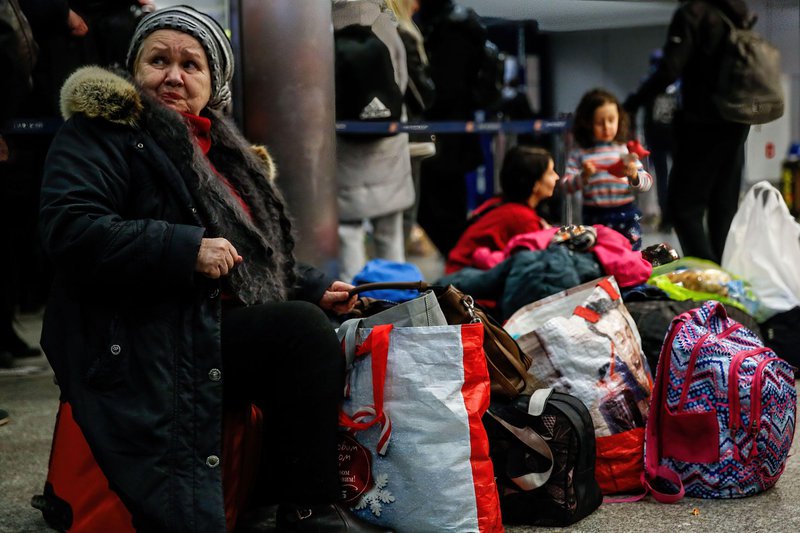 Ukrainian woman rests on her luggage after arriving at the main railway station in Krakow as more than million people already fled Ukraine for Poland