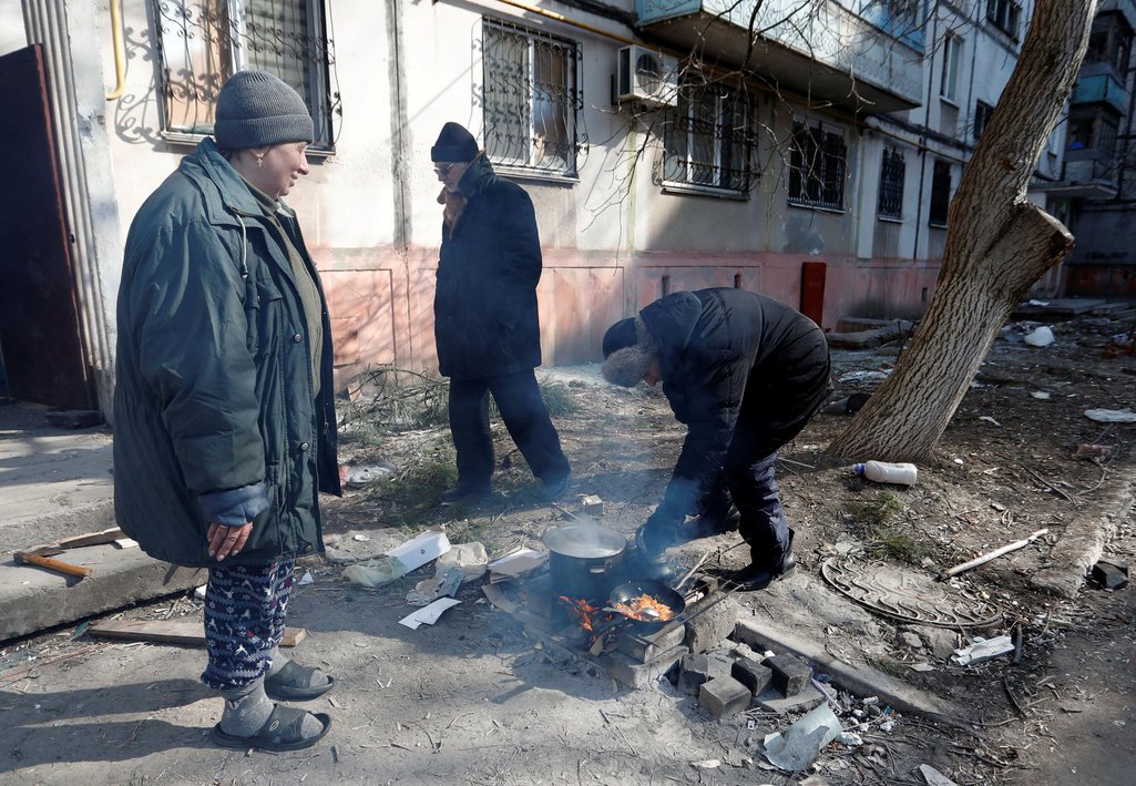Local residents cook outside a residential building during Ukraine-Russia conflict in the besieged southern port city of Mariupol, Ukraine March 18, 2022