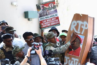 The leader of Operation Dudula, Nhlanhla 'Lux' Dlamini, wearing paramilitary-style clothes rips a picture of Economic Freedom Fighters (EFF) leader Julius Malema on a coffin outside magistrate's court in Roodepoort, South Africa, March 28, 2022