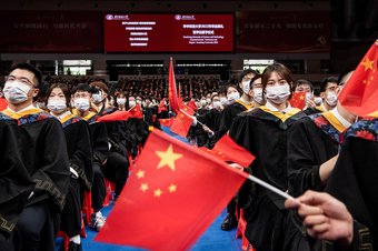 Chinese students from Huazhong University of Science and Technology wave flags during the graduation ceremony in the school's gym, 22 June 2022