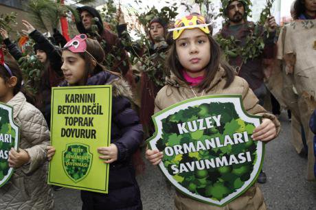 Northern Forest Defence activists with two young children at forefront in forest colours holding banners