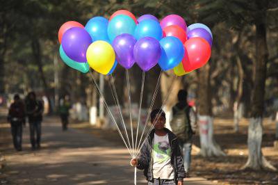 A 10 year old Bangladeshi migrant child selling ballons to earn money for his climate change refugee family