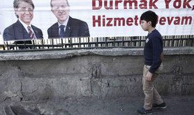 Boy walks past an election poster featuring Turkish PM Erdoğan