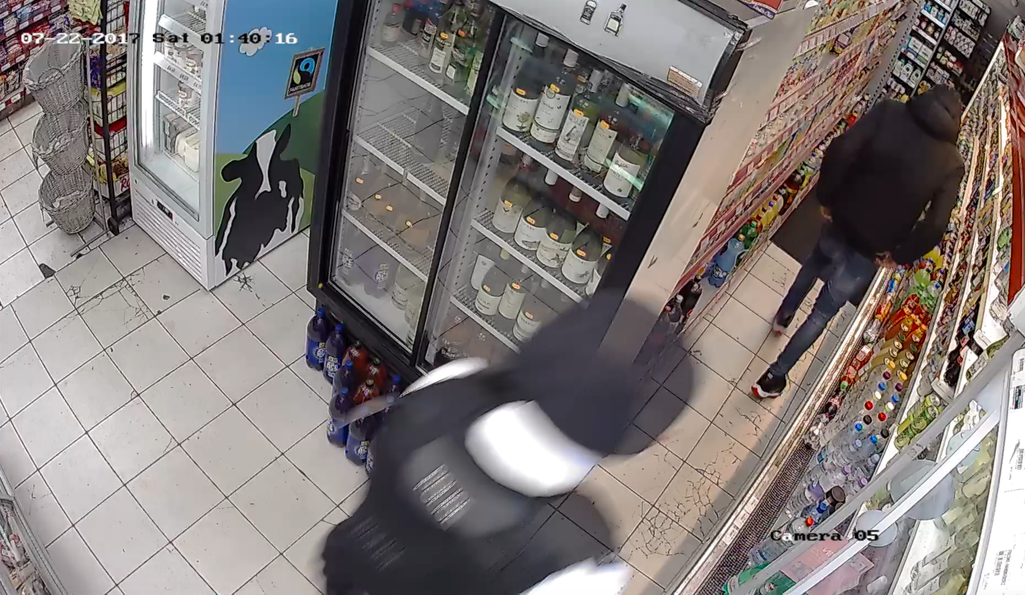 Police officer pursing young man inside a small convenience shop