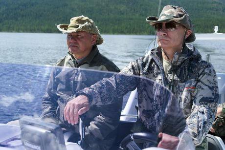 Shoigu and Putin in camouflage gear in a small fishing boat. 
