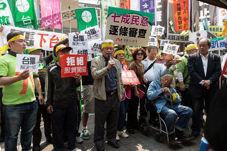 Political dissident Su Beng sits in a wheelchair listening to speeches at an anti-government protest