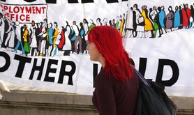 A woman walks past an anti-austerity placard on the Southbank.