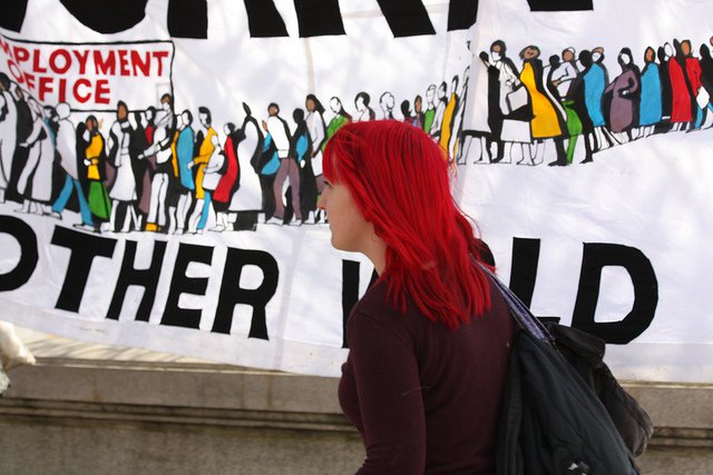 A woman walks past an anti-austerity placard on the Southbank.
