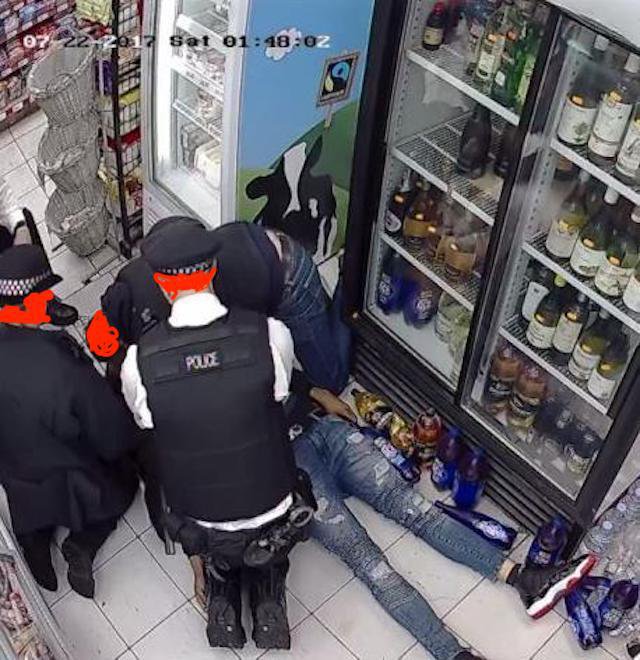 Two police officers and man lean over young man lying still on the floor.