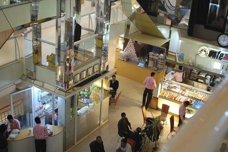 A shiny and modern coffee shop attended to by several employees in a large shopping centre.