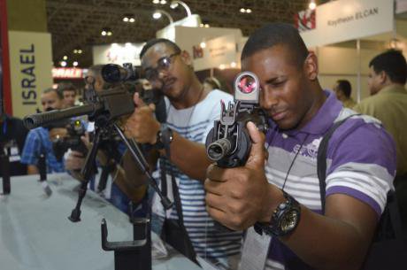 Two men holding guns in the LAAD Defence and Security Fair 2015, Rio de Janeiro. 