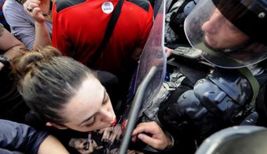 Woman applies lipstick in riot shield in Macedonia