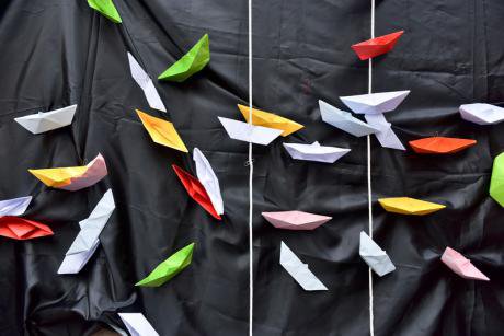 Protest at Palermo port, paper boats on black cloth representing the Mediterranean.