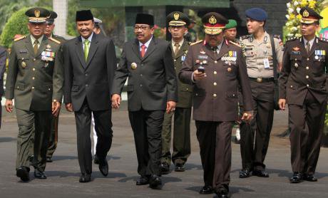 A group of civil, military, and police personnel are walking during an anniversary ceremony