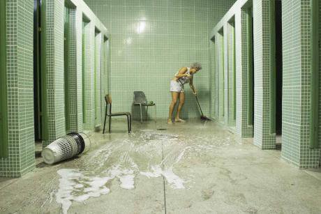 A female student mopping the floor of the school bathroom