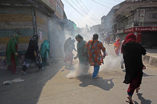 People in Kashmir, India, running through the streets in a cloud of tear gas