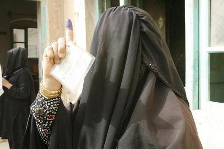 A burqa-clad woman shows her inky finger and her card after casting a vote at a polling station in Istalif, Sept 2010