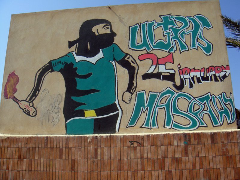 Graffitied wall with image of molotov cocktail-holding ultra and '25th January'.
