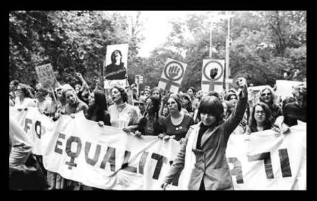  Women march behind &#39;March for Equality 1971&#39; banner, while women at front raises her left fist