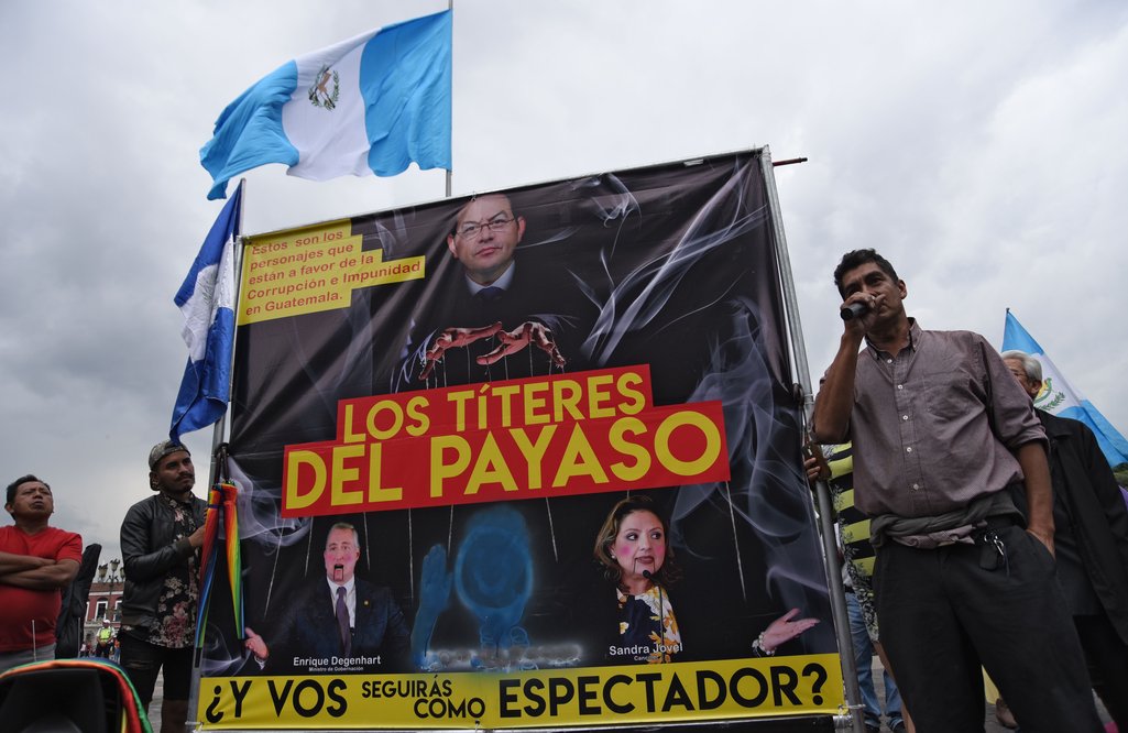 Personas se manifiestan en apoyo a la Comisión Internacional contra la Impunidad en Guatemala (CICIG) con un cartel que representa al presidente guatemalteco Jimmy Morales en el que se lee 