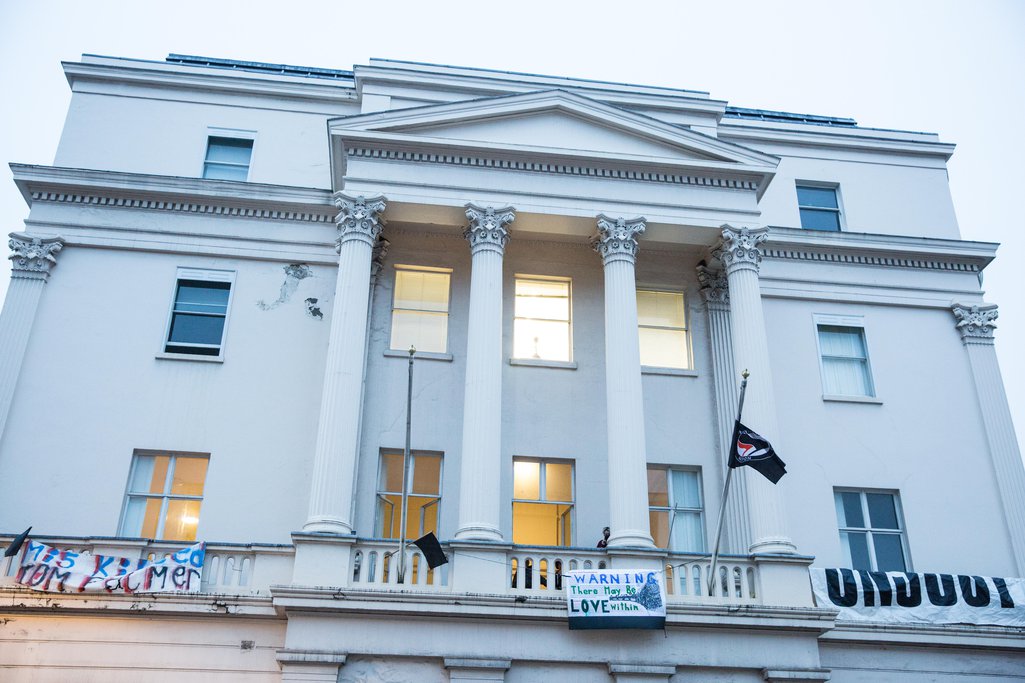 An anarchist flag flies from a mansion
