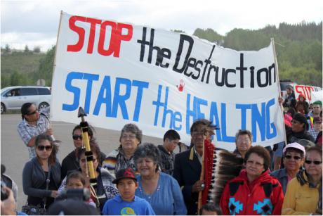 People hold a 'Stop the destruction - start the healing' banner