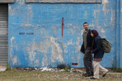 Man and woman walking side-by-side in front of blue wall