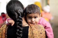 A Bangladeshi woman holds her baby daughter over her shoulder.