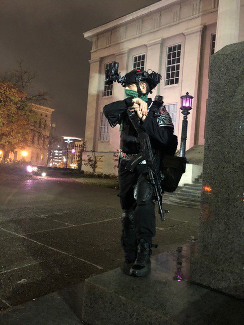 Masked White man with a rifle outside Louisville public library, protecting Black Lives Matter protestors, 29 October 2020