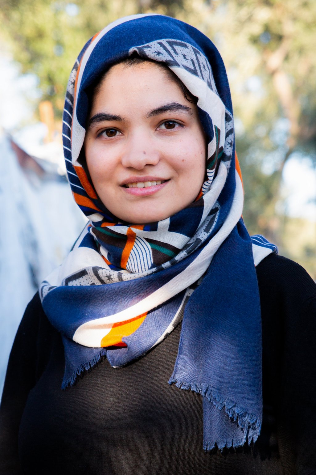 A portrait photo of a young Afghan woman in a headscarf