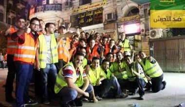 Posed group photo of about twenty young men in high-visibility jackets.