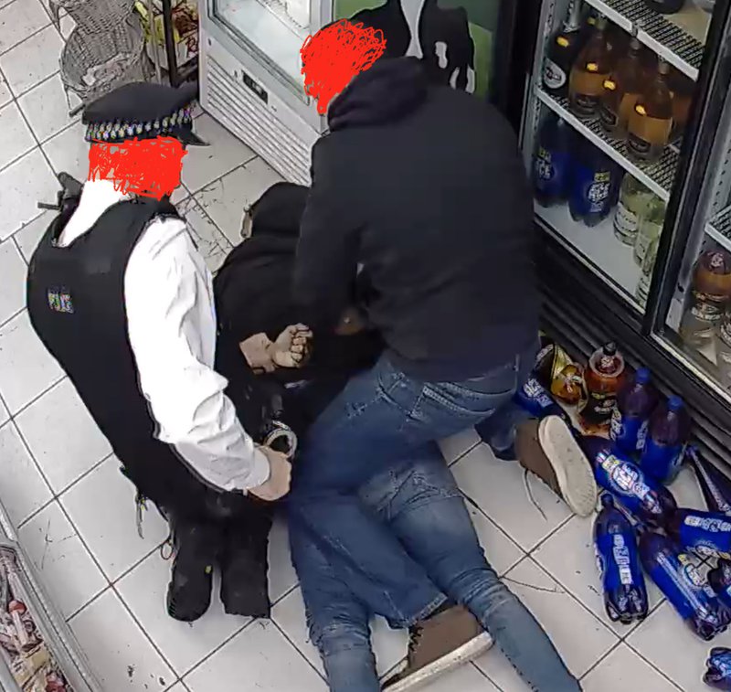 Police officer and second man handcuff young man lying limp on ground