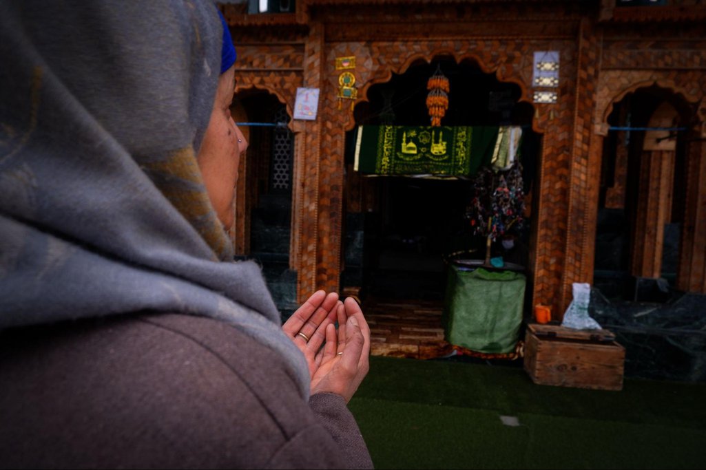 Naseema praying before entering the shrine in Aishmuqam
