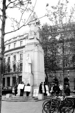 Black and white photo of women dressed in black with signs surrounding a monument