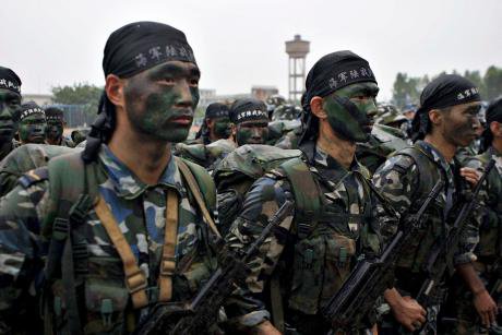 Chinese marines drill. They are armed and their faces are covered in war paint.
