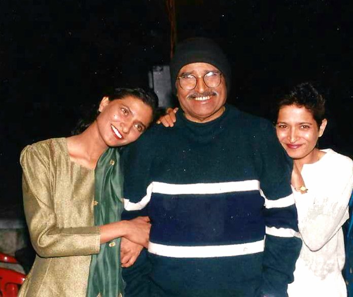 Gauri and Kavitha stand either side of their father, with their arms around him