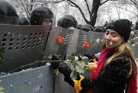 An Orange protester gives a flower to a uniformed riot police officer. 