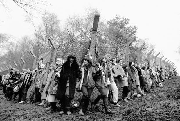Black and white image of women surrounding RAF Greenham Common air base in a protest in 1982