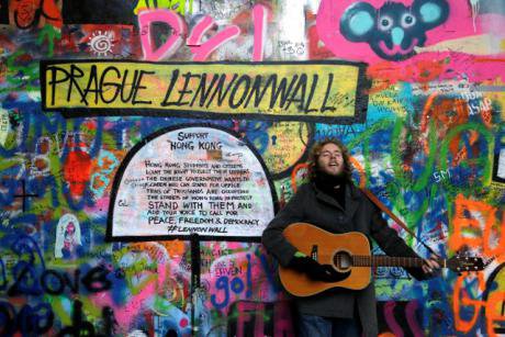 A musician at Prague&#39;s famous &#39;Lennon Wall&#39; plays in support of democracy activists in Hong Kong. (AP Photo/Petr David Josek)